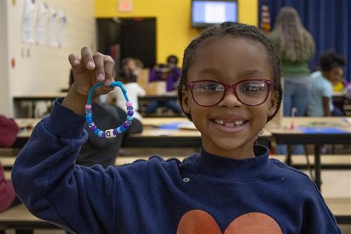 Student holds up bracelet