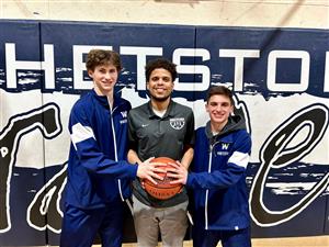 player and coach holding a basketball and smiling at camera