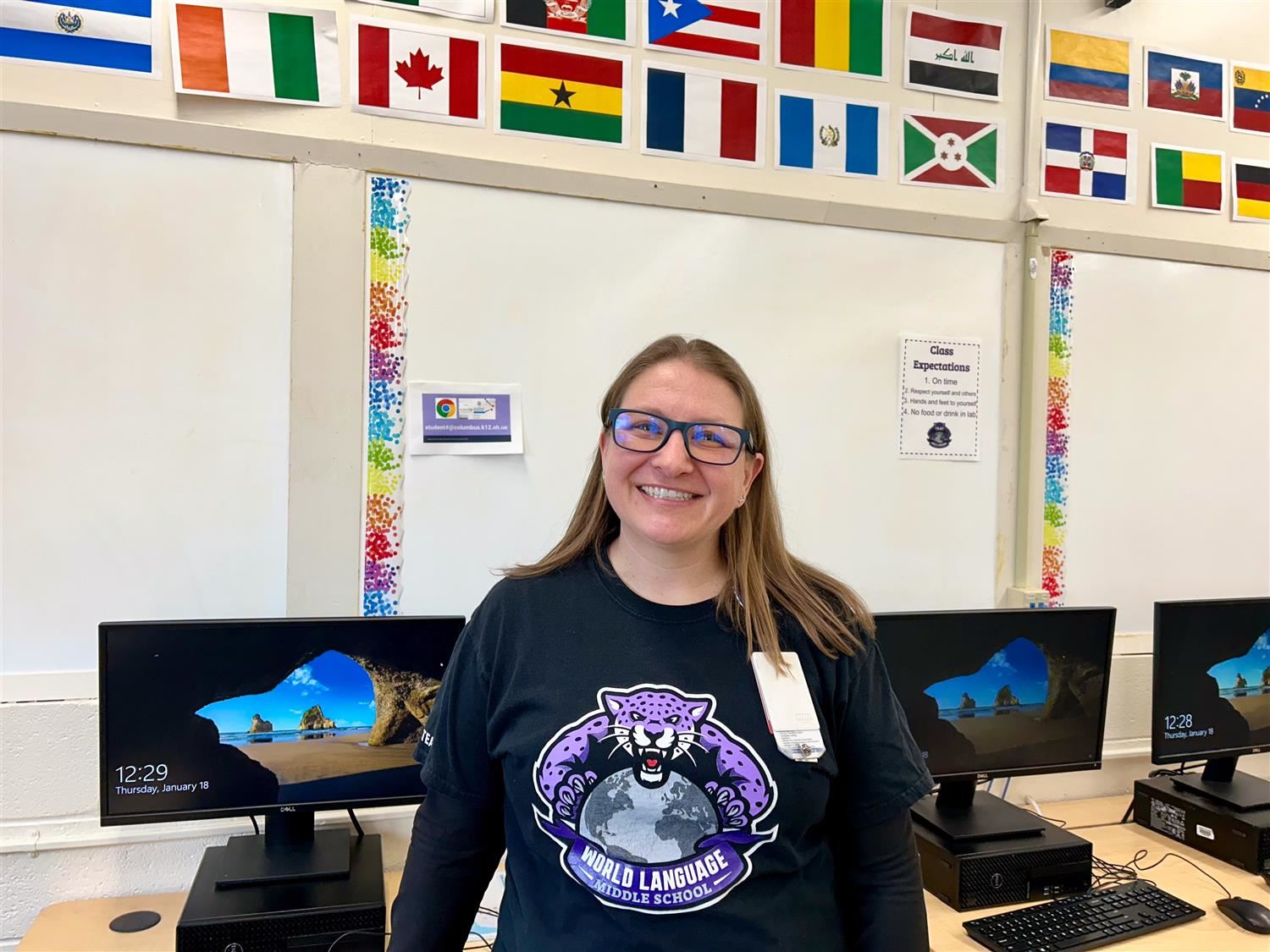Teacher Smiling Brightly wearing a black long sleeved shirt in front of computers
