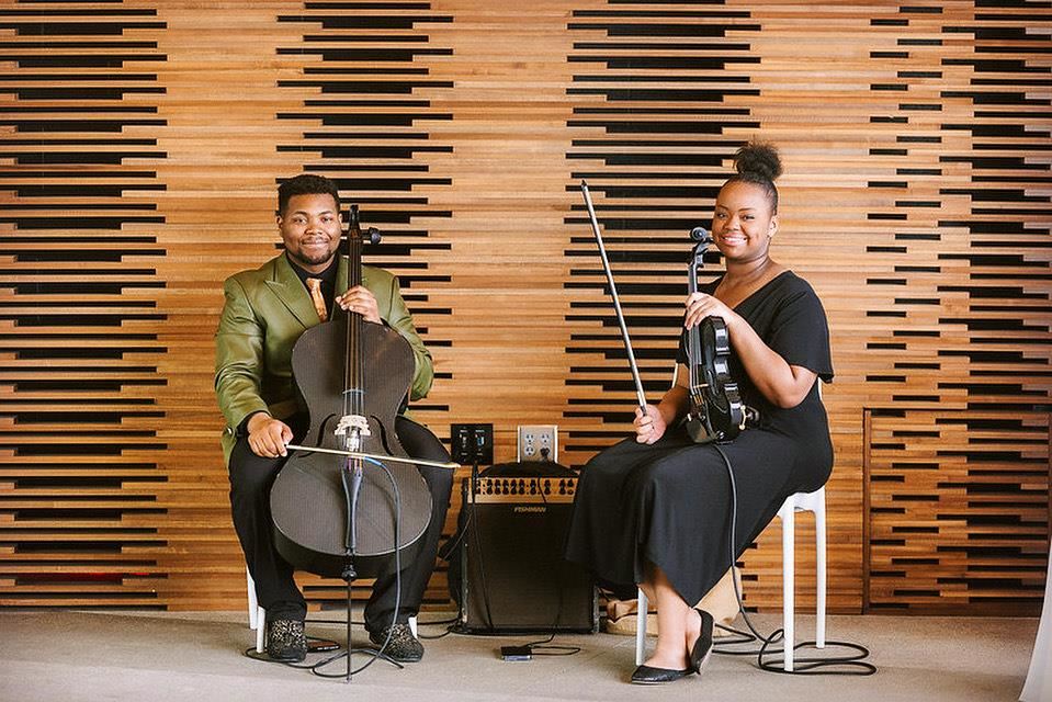 two string performers sitting in chairs