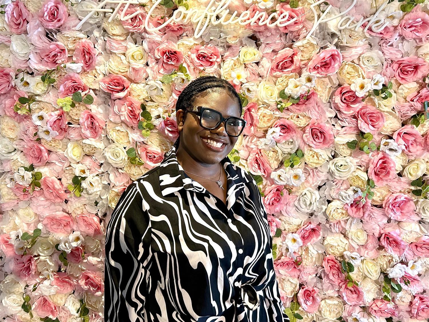 senior standing in front of floral backdrop
