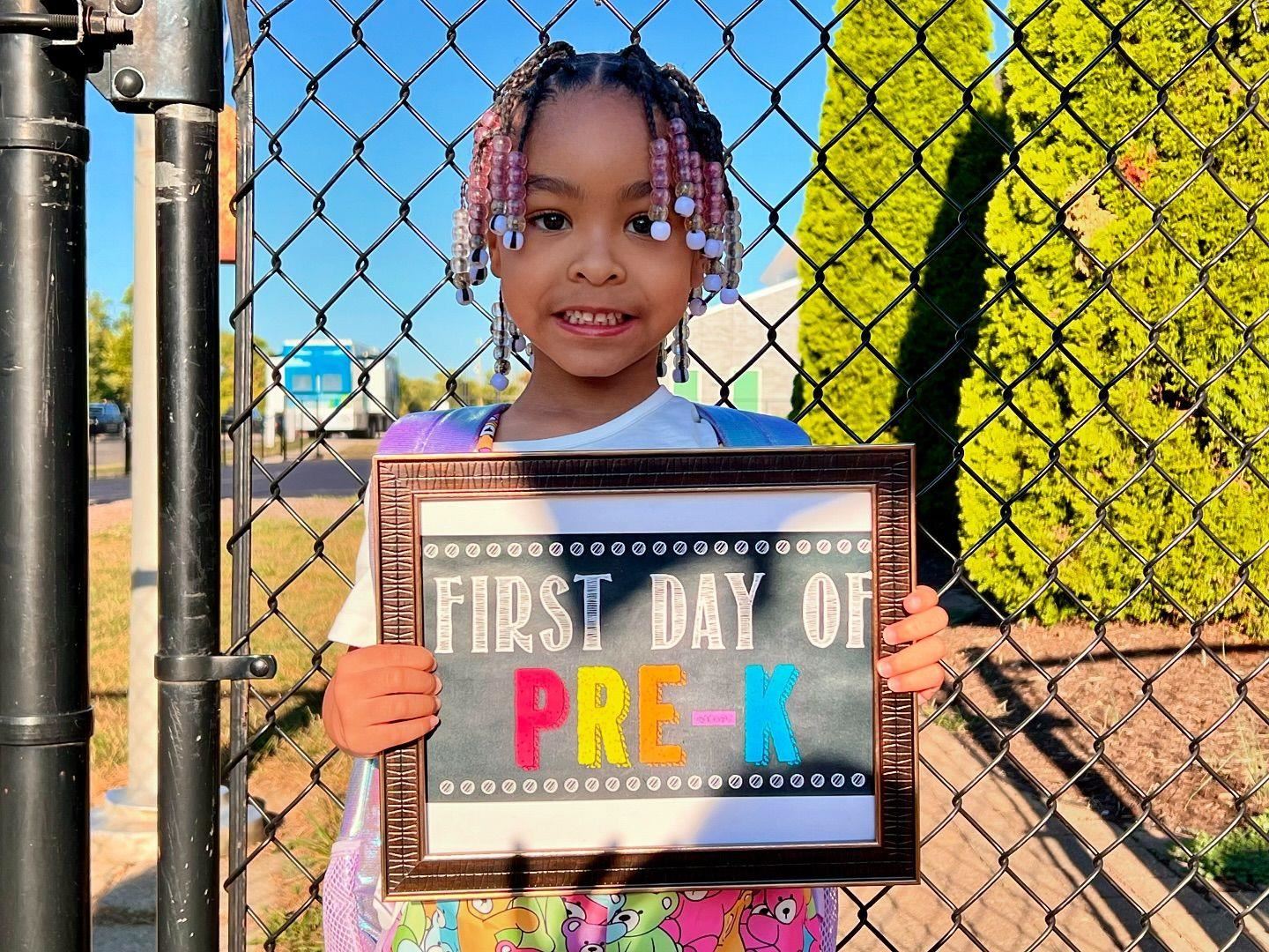 girl smiling first day of pre-k sign