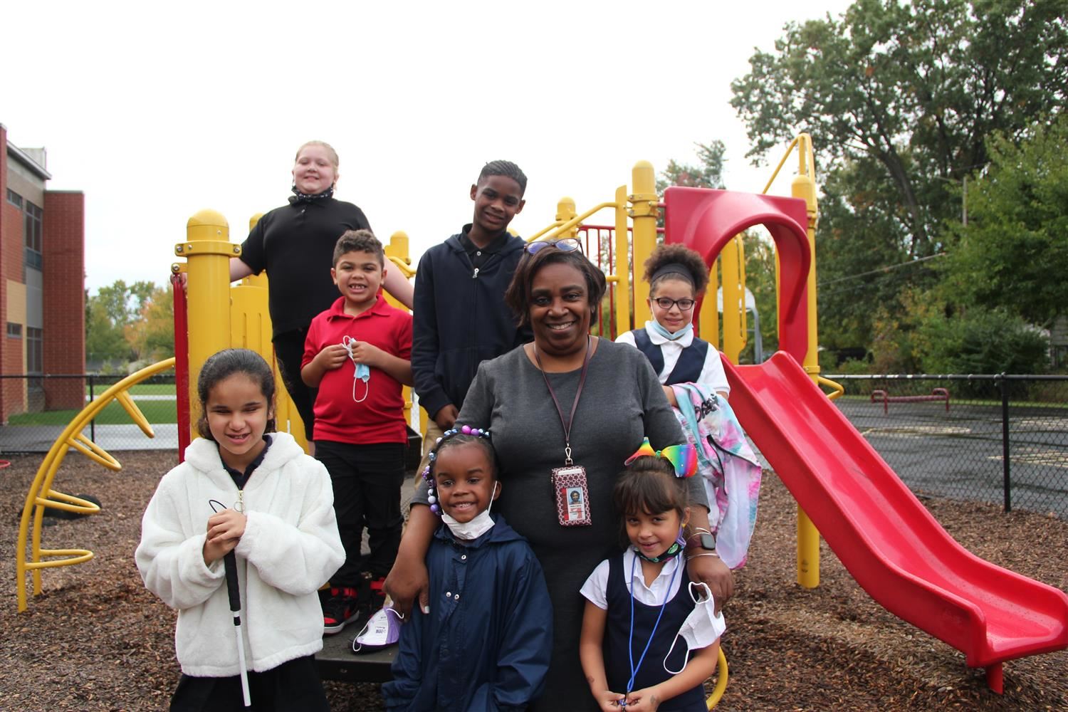 Principal Malik poses for a photo with students on the playground