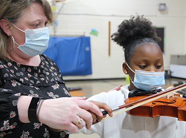  Teacher helps a student play violin